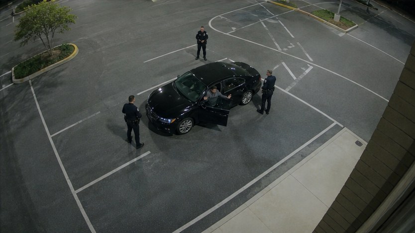 Fictional fixed CCTV view looking down on the sedan and three officers