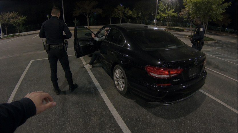 Fictional Officer Patel body-camera view from the rear quarter of the sedan